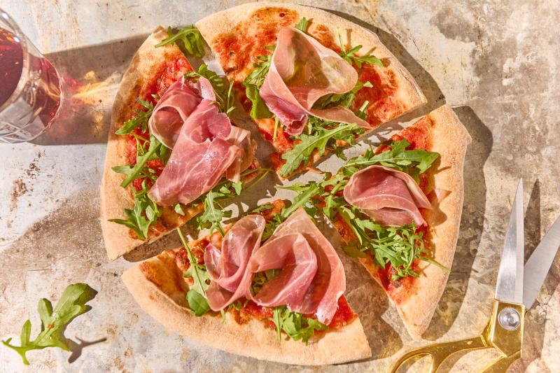 Persze, íme egy egyedi leírás a prosciutto pizzáról:

Képzelj el egy ropogós, aranybarnára sült pizzatésztát, amelynek szélein egy kicsit megpirultak a falatok. A pizza alapját egy gazdag, fűszeres paradicsomszósz borítja, amely tele van friss bazsalikomm
